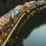 Negotiating Markets - white canopy with stores near body of water during daytime