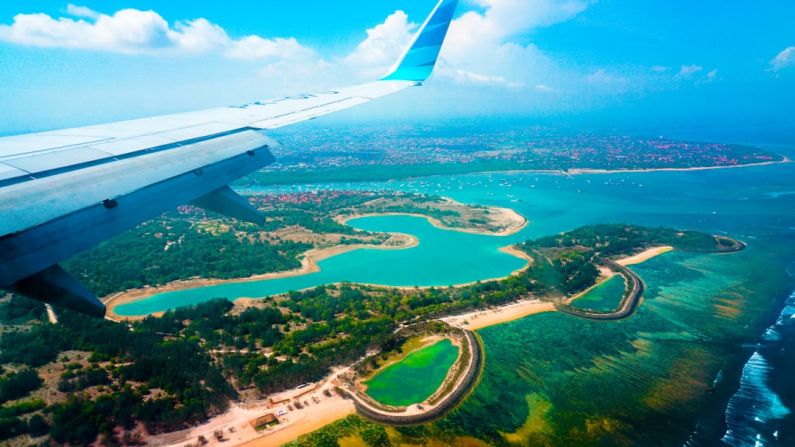 Bali Island - person inside airplane flying at high altitude with view of island during daytime