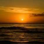 Secret Beach - a sunset over the ocean with a boat in the distance