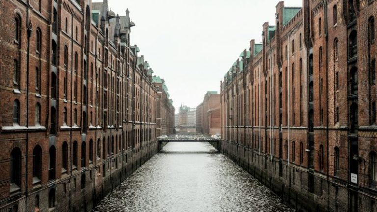 Amazon City - body of water between brown concrete buildings during daytime