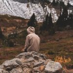 Mountain Retreat - a person sitting on top of a large rock