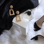 Luxury Spots Budget - pair of gold-colored earrings on table and black ankle-strap pumps on area rug