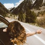 Travel Safety - woman riding on vehicle putting her head and right arm outside the window while travelling the road