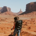 Solo Travel - woman with black backpack standing on brown dessert