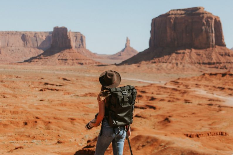 Solo Travel - woman with black backpack standing on brown dessert